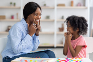 Speech therapist working with little girl at clinic